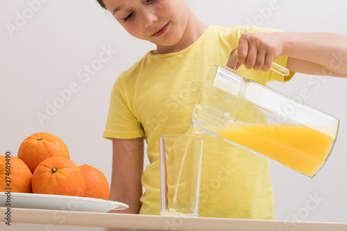 child pours orange juice into a glass