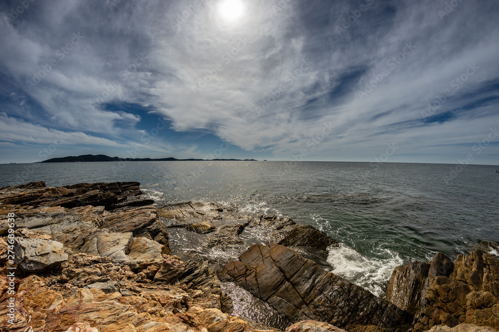 Horizon Brown Rocks on Sea shore with Blue Cloudy sky