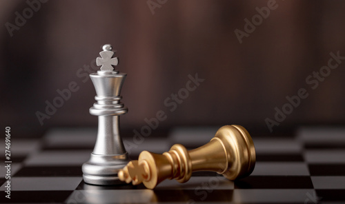 silver king standing and gold falling on chess board