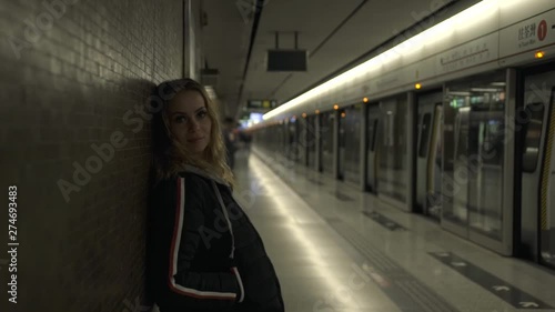 Tourist woman on subway underground looking to camera. Portrait young woman on subway station waiting train. Chinese uderground interior. Travel and tourism concept. photo