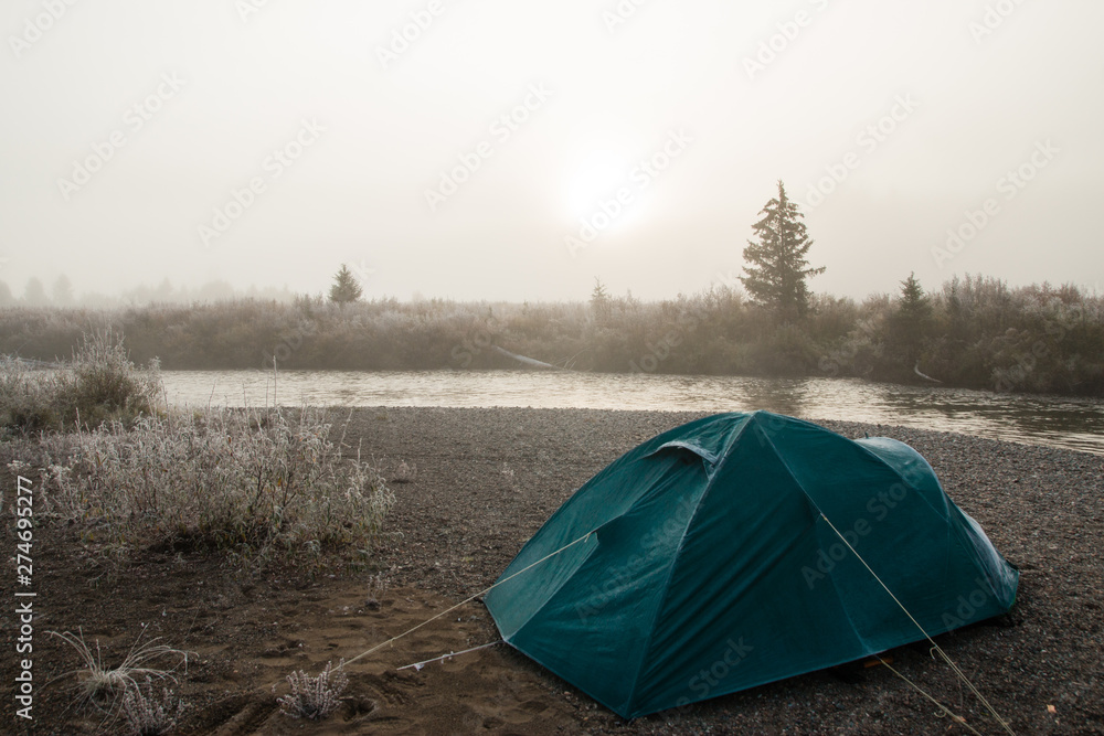 Camping in a clearing in the morning. fog, river, mountains. Tent in the camping in the evening. the rest of the group of people