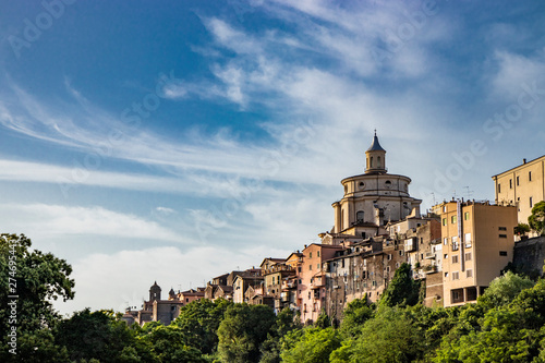 A view of the city of Zagarolo, with the houses built sheer above a tuff hill. Above the roofs the dome of the church of San Pietro appears. The valley full of trees. Province of Rome, Lazio