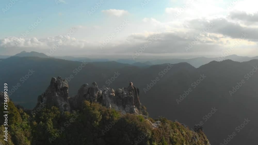 Aerial drone pull-out shot flying away from two hiker men sitting on a cliff at The pinnacles of New Zealand Aerial drone pull-out shot flying away from two hiker men sitting on a cliff at The pinnacles of New Zealand