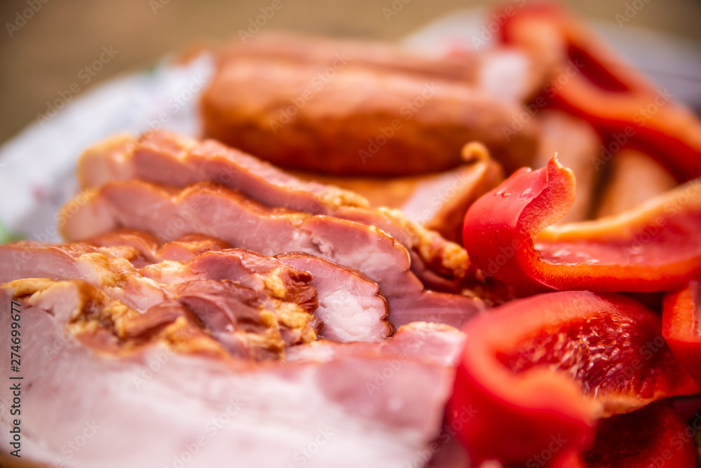 Close up of raw bacon, sausages and paprika on colorful tray, prepared for barbecue