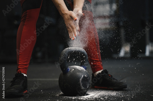 Closeup of crossfit female athlete claping hands with cloud of dust while magnesia protection.