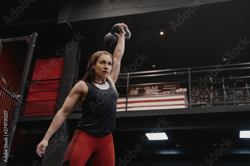 Strong crossfit woman exercising with a kettlebell at the gym. Female doing functional training