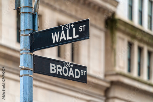 Wall Street "WALL ST" sign and broadway street over  NYSE stock market exchange building background. The New York Stock Exchange locate in economy district, Business and sing of landmark concept © THANANIT