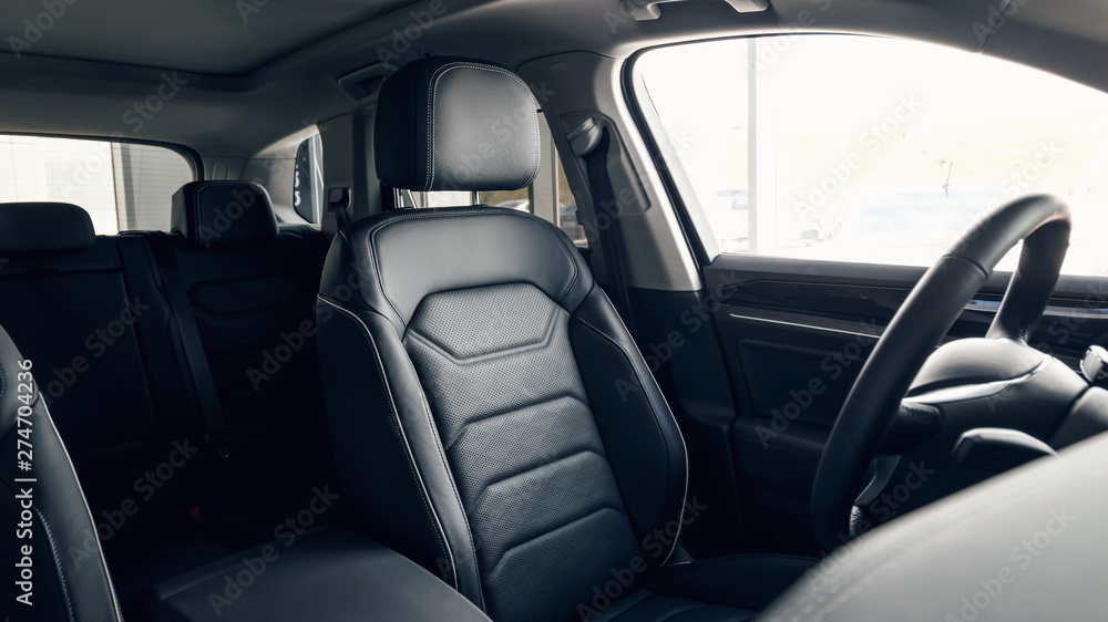 Black leather car interior. Modern car interior dashboard and steering wheel. Modern luxury car black perforated leather interior. Interior details