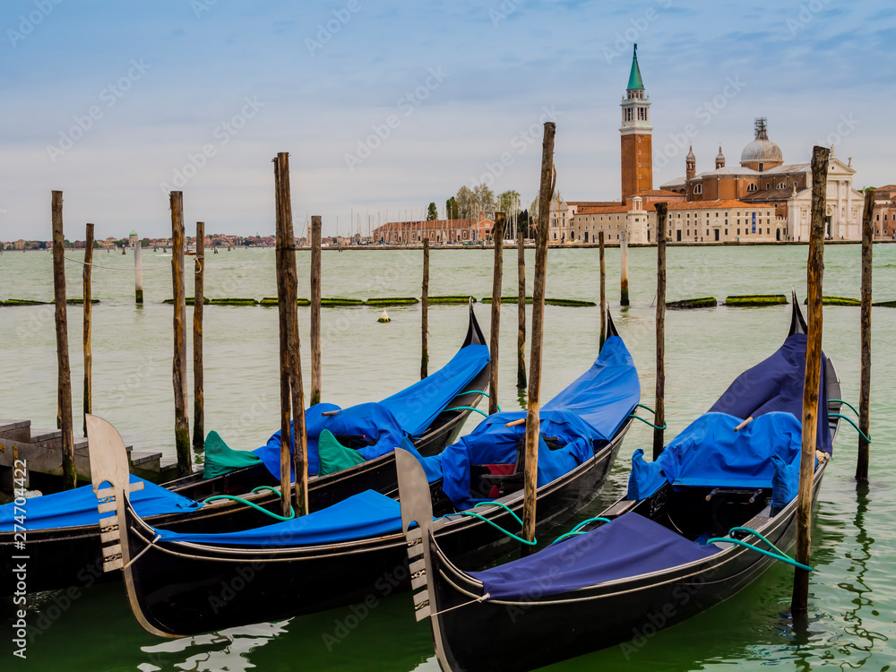 Row of gondolas moored on the lagoon in front of San Giorgio Maggiore island, Venice, Italy