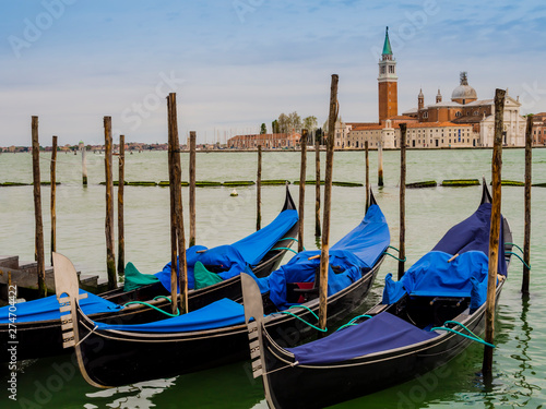 Row of gondolas moored on the lagoon in front of San Giorgio Maggiore island, Venice, Italy