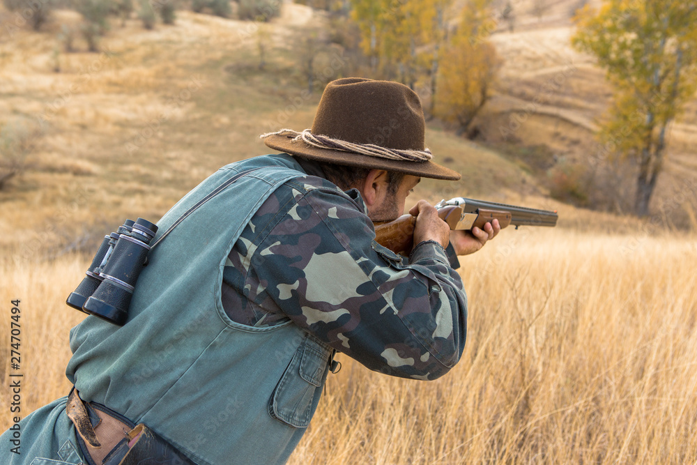 Hunter with a hat and a gun in search of prey in the steppe Hunter with a hat and a gun in search of prey in the steppe