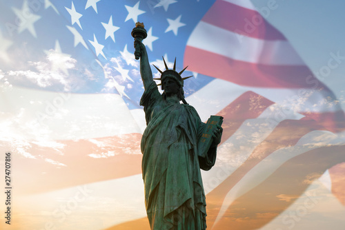 Double exposure with statue of liberty and United States flag blowing in the wind.