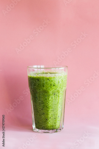 Healthy green smoothie with kiwi in a glass Cup on a pink background