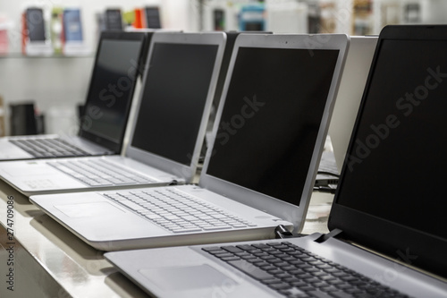 A row of laptops in computer shop. Closeup, selective focus photo