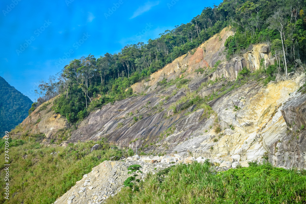 Landslide on cliff of mountain with jungle
