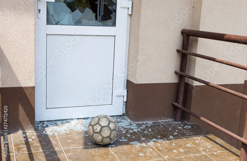 A soccer ball broke the window. Football and broken window glass. Close-up, selective focus. photo