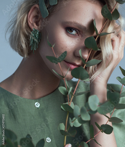Fashion portrait of blonde female model on grey background. stylish green clothes and accessories. concept of garmonical style and atmosphere
