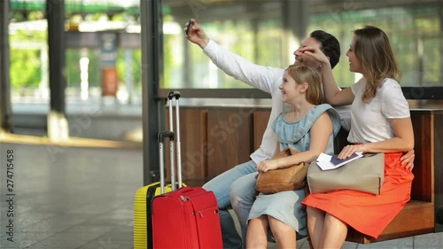 Vacation Time Rocks. Smiling Beautiful Family Taking Selfie With Smartphone While Waiting For Their Flight At Airport or Train At Railway Station.