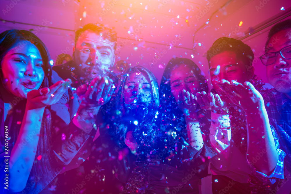 People on a party in the nightclub.group of friends celebrate party and throwing confetti while enjoying home Young company celebrates birthday with a cocktail in hand. - obrazy, fototapety, plakaty 
