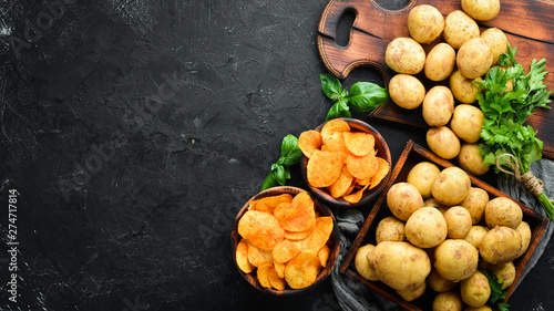 Potatoes and potato chips on a black background. Organic food. Top view. Free space for text.