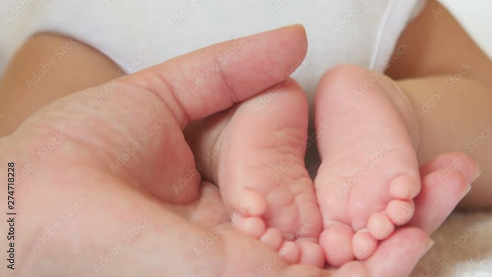 Mother gently holds in her hand the small legs of her newborn baby, motherhood. Mom and her Child. Happy Family concept. Mother gently holds in her hand the small legs of her newborn baby, motherhood. Mom and her Child. Happy Family concept.