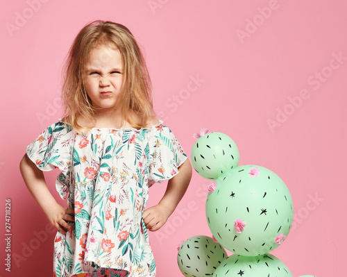 Young blond girl 4 years old holding a cactus ball in a pastel pink wooden box. The flowers are made of balloons with pink flowers and painted spines photo