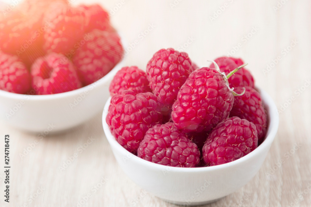Fresh raspberries in white ceramic cup on white rustic wooden background with copy spice Fresh raspberries in white ceramic cup on white rustic wooden background with copy spice