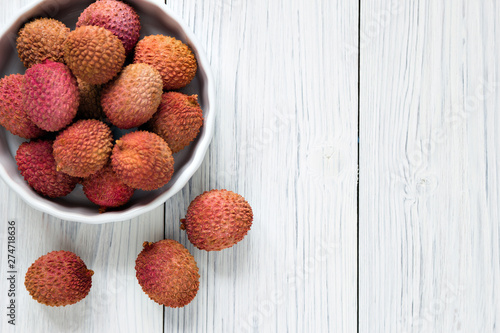 Fresh lychee in white bowl on a wooden background with copy spice