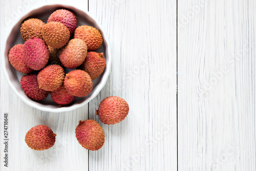 Fresh lychee in white bowl on a wooden background with copy spice