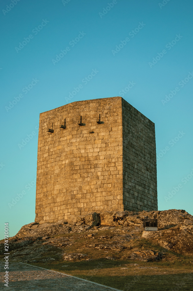 Stone square tower over rocky hill on sunset Stone square tower over rocky hill on sunset