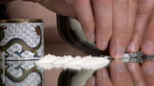 This closeup video shows a person snorting lines of cocaine drugs using a rolled hundred bill.