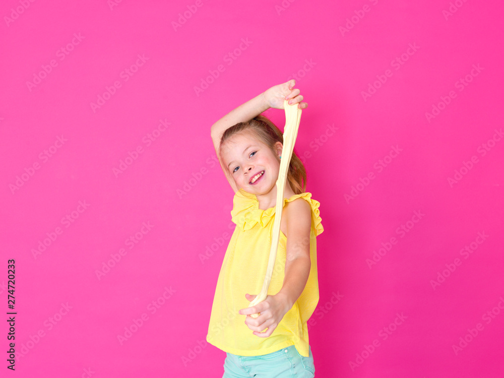 beautiful 10 year old girl is playing with yellow slime in front of pink background and is happy beautiful 10 year old girl is playing with yellow slime in front of pink background and is happy