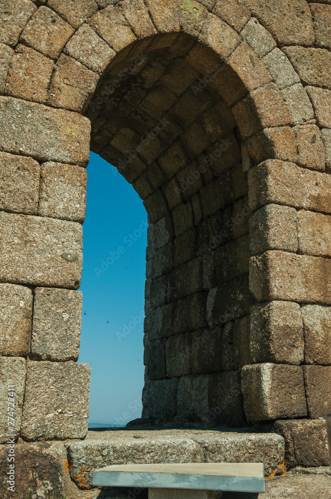 Arched gateway on stone wall over rocky hill