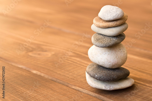 Balance the stones on the wooden table.