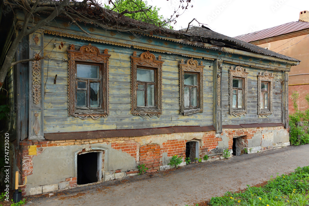 Abandoned old residential wooden house on a brick foundation with carved platbands on the windows in a russian town Abandoned old residential wooden house on a brick foundation with carved platbands on the windows in a russian town