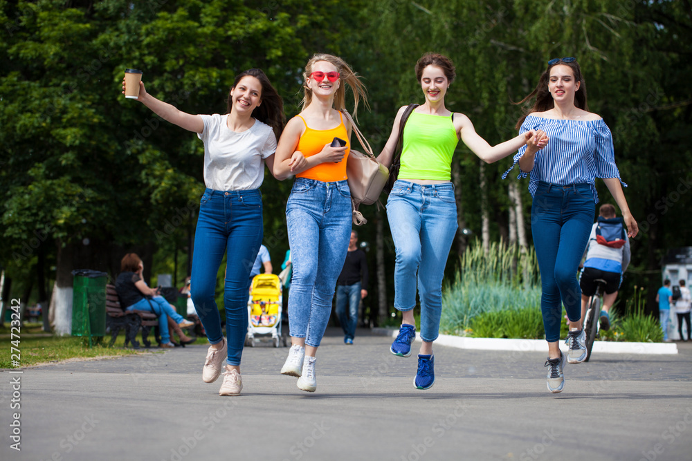 Happy women in blue jeans walking in summer park Happy women in blue jeans walking in summer park