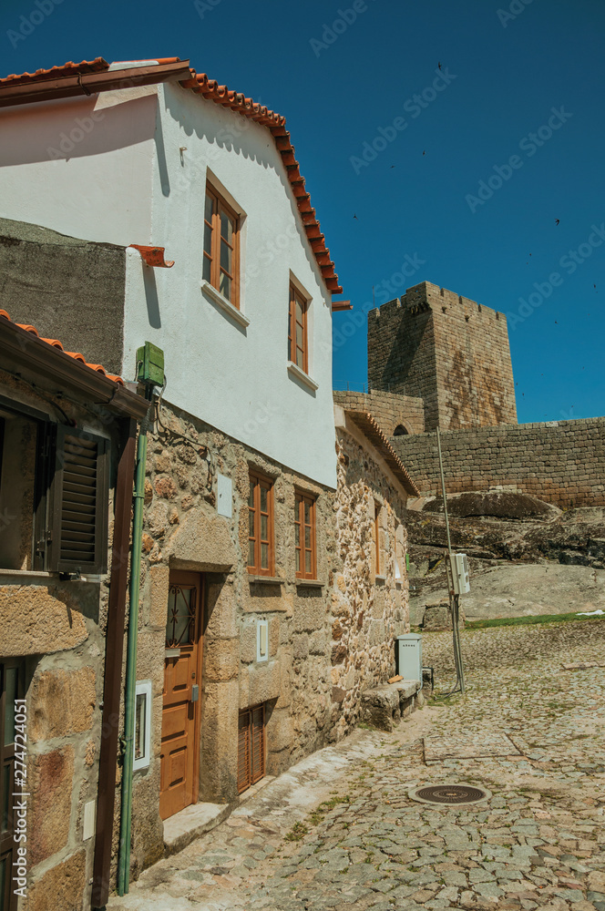 Rustic house in front of stone wall and square tower