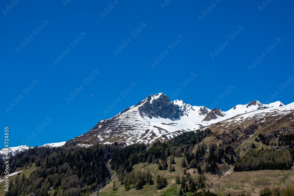 Panorama from the Davos lake -Switzerland with high partial snowy mountains of the Alps in spring at sunshine and blue sky