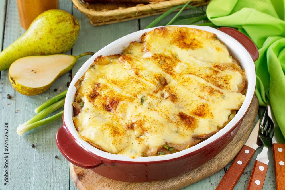 Potato gratin with pear, raclette cheese, and bacon on rustic wooden table. Traditional french cuisine. Potato gratin with pear, raclette cheese, and bacon on rustic wooden table. Traditional french cuisine.