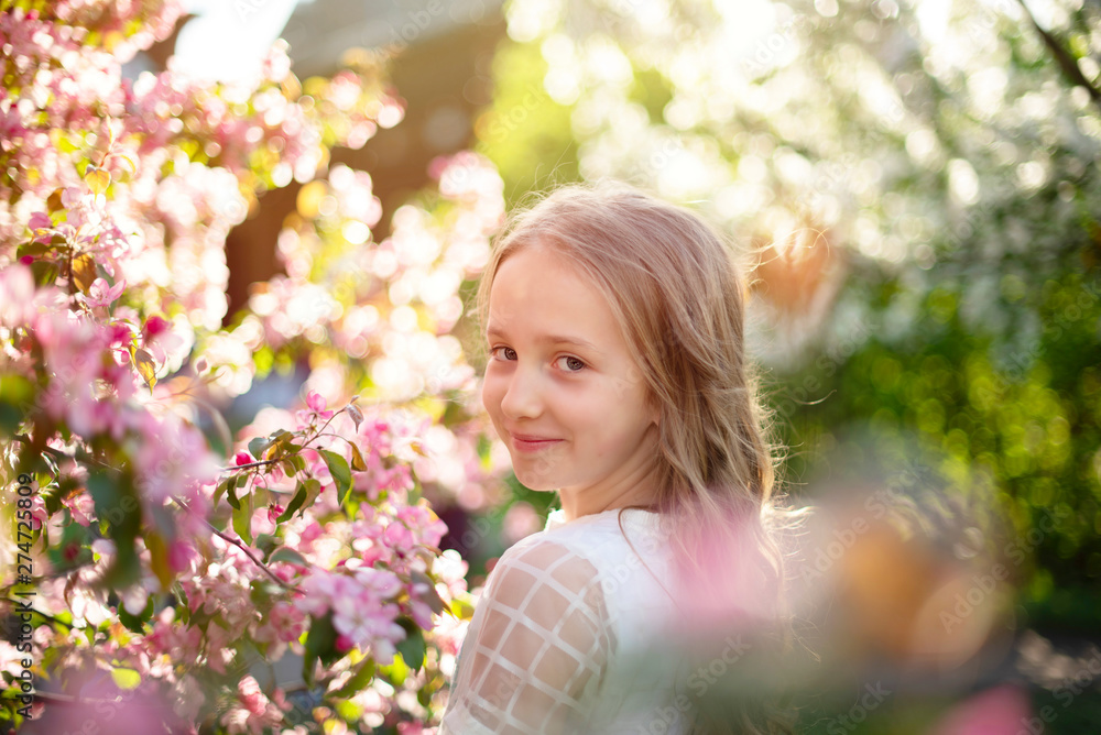 Fototapeta premium candid portrait of a girl in a blooming apple orchard