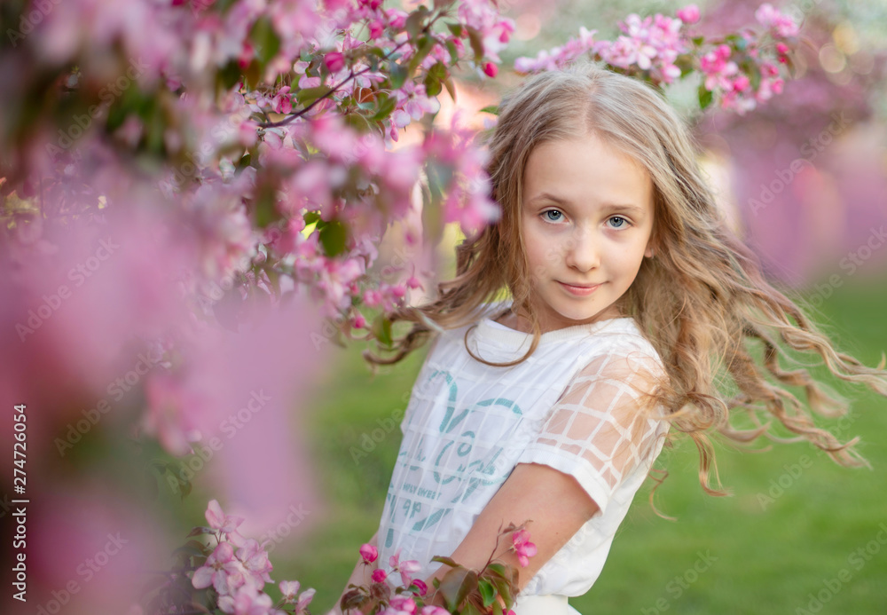 Fototapeta premium candid portrait of a girl in a blooming apple orchard