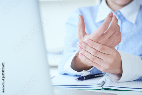 Young woman holding her wrist close-up . Pain from using computer. Office syndrome hand pain by occupational disease.