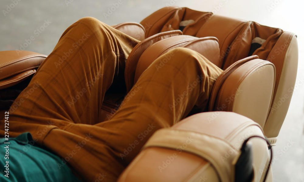 Φωτογραφία Closeup of legs of a man relaxing on the electric massage chair