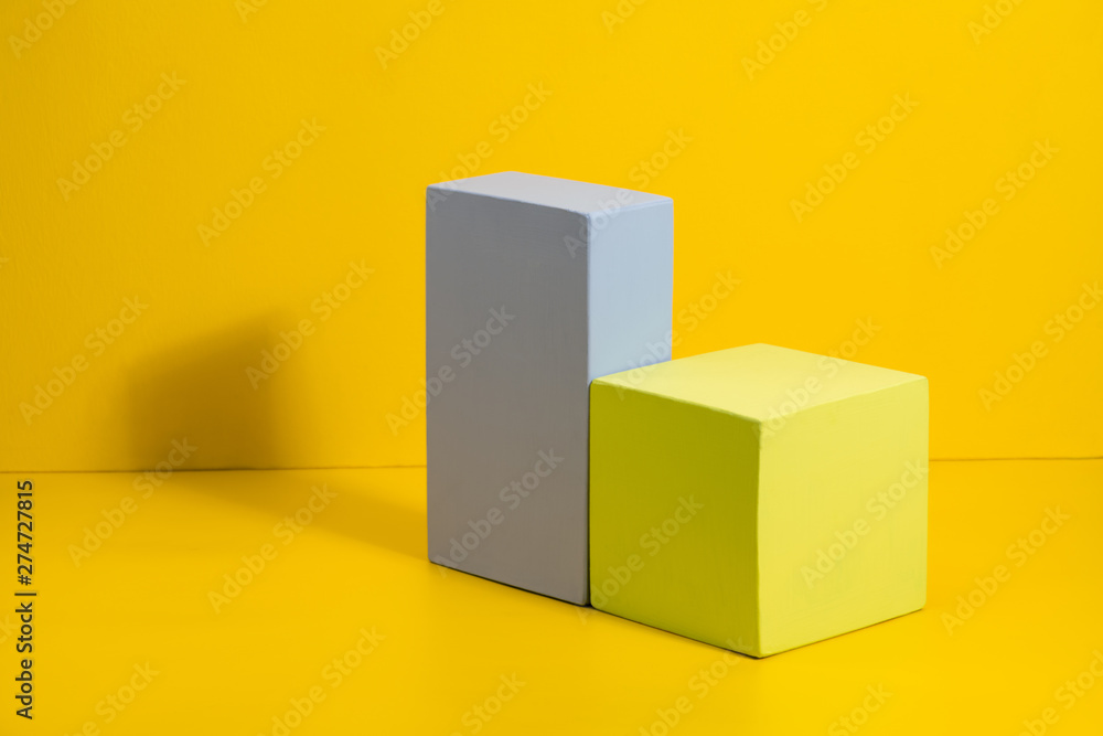 Geometric shapes in different colors on yellow background. Three-dimensional solid figures on colored paper. Geometric shapes in different colors on yellow background. Three-dimensional solid figures on colored paper.
