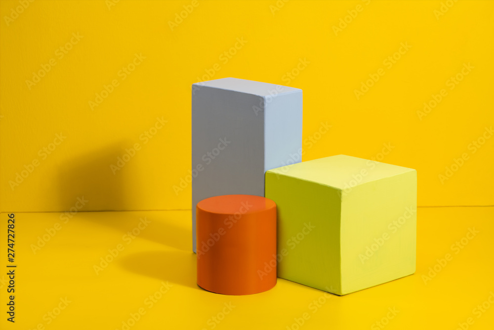 Geometric shapes in different colors on yellow background. Three-dimensional solid figures on colored paper. Geometric shapes in different colors on yellow background. Three-dimensional solid figures on colored paper.