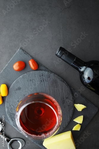 Wine glass and black wine bottle. Nuts cheese and tomatoes for snack.