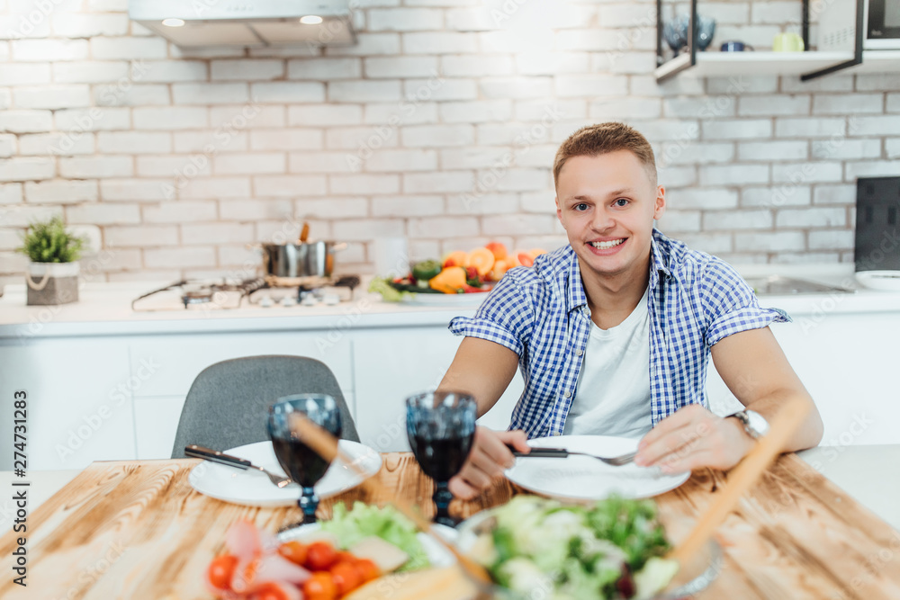 Handsome young man waiting his girl at home kitchen with red wine.. Handsome young man waiting his girl at home kitchen with red wine..