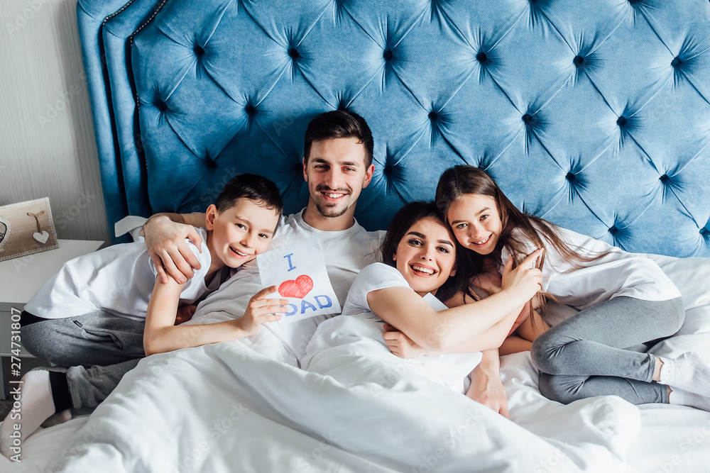 Photot of happy family with two children sitting at home , children make a presents for parents.