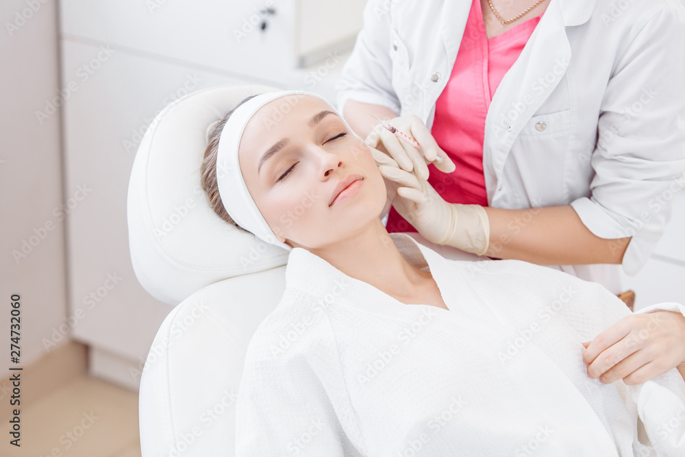 Close-up master cosmetologist makes injection of hiluronic acid in the face of a beautiful young woman. The concept of modern anti-aging procedures in the beauty salon Close-up master cosmetologist makes injection of hiluronic acid in the face of a beautiful young woman. The concept of modern anti-aging procedures in the beauty salon