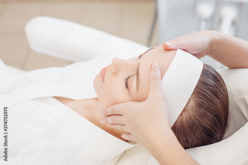 Fototapeta premium Unknown masseuse beautician doing a face massage to her client a beautiful young woman. Skin care concept